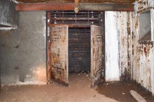 Ligne Maginot - 113 - OLTINGUE - (Casemate d'artillerie) - Chambre de tir coté gauche. Vue donnant sur l'entrée des munitions avec la porte  à 2 battants entrouverte et les rails de protection en place. Cette chambre est plus petite que celle de droite du fait de l'absence de couloir vers l'entrée des hommes qui se fait par la chambre de tir de droite.