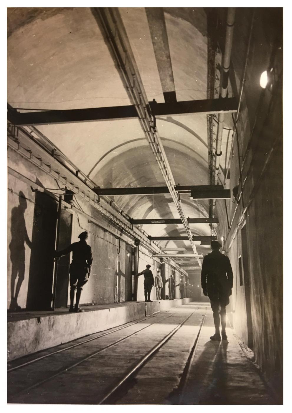 Ligne Maginot - HACKENBERG - A19 - (Ouvrage d'artillerie) - Magasin à munitions M1, voie de sortie des plateformes Péchot (deux voies parallèles, à gauche celle du chargement de wagonnets vers les blocs et à droite celle d'échappement des Péchot vides). Noter là encore la 'mise en scène' et l'éclairage travaillé, peu conforme à la vie réelle...
On aperçoit aussi le quai de chargement des wagonnets à partir des cellules à munitions - Inconnu