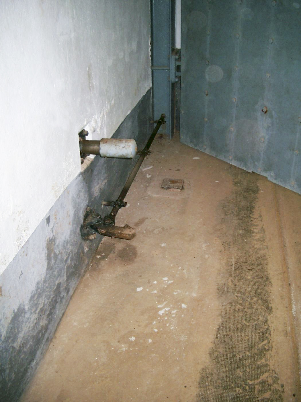 Ligne Maginot - GALGENBERG - A15 - (Ouvrage d'artillerie) - Porte pare-souffle. Crochet de maintien et butée-ressort en position porte fermée. La petite plaque métallique au sol et la découpe dans la tôle correspondent à une roulette métallique d’appui en position ouverte.